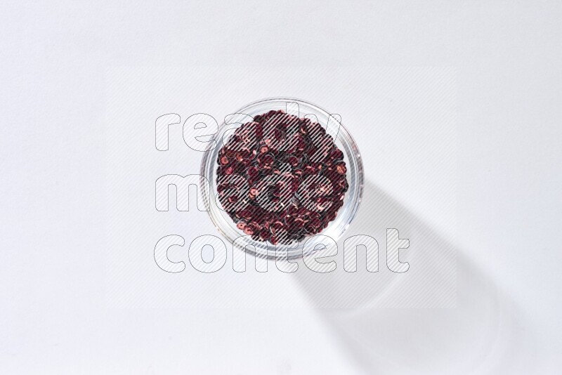 Colored flat sequins in a glass bowl on grey background