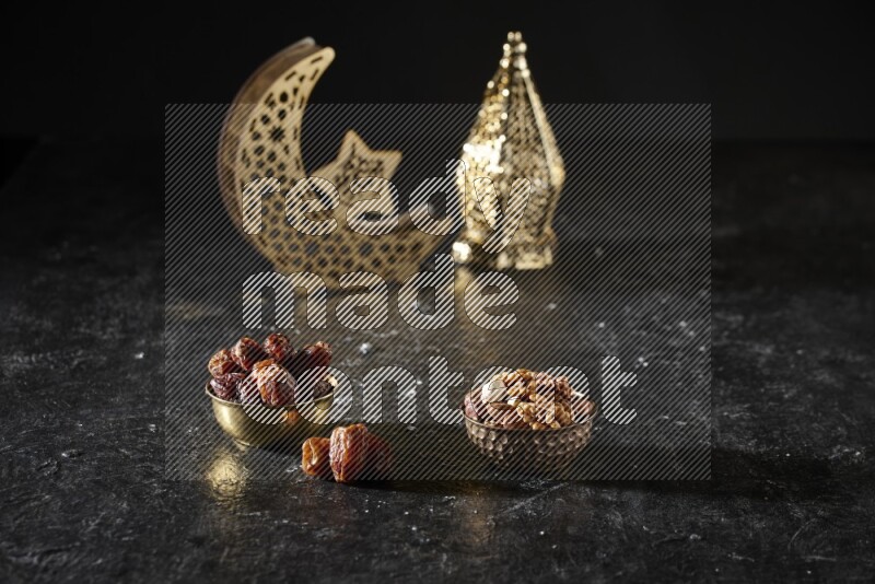 Dates in a metal bowl with mixed nuts beside golden lanterns in a dark setup