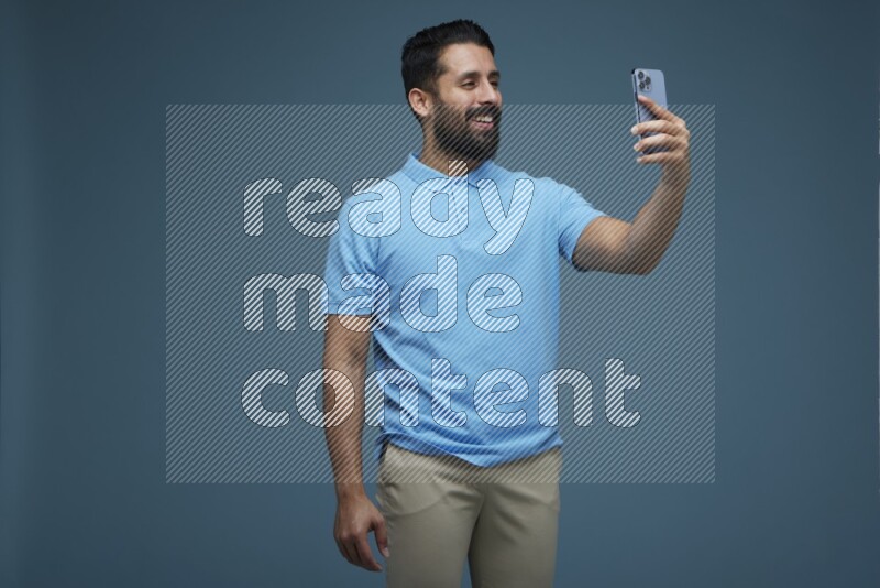 Man Taking a Selfie in a blue background wearing a Blue shirt