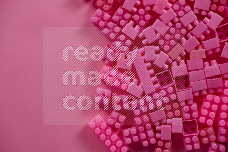 Pink plastic building blocks on pink background (kids toys)