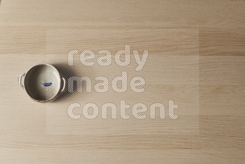 وعاء فخاري متعدد الألوان على خلفية خشبية فاتحة