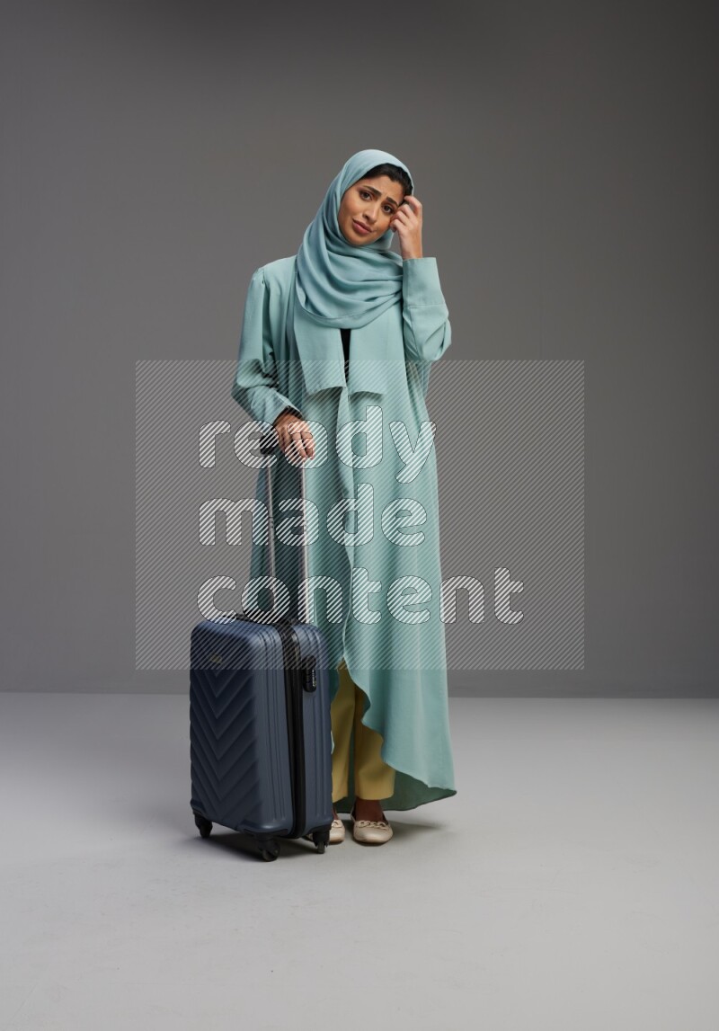 Saudi Woman wearing Abaya standing holding Travel bag on Gray background