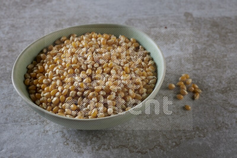 corn kernel in a green ceramic bowl on a grey textured countertop