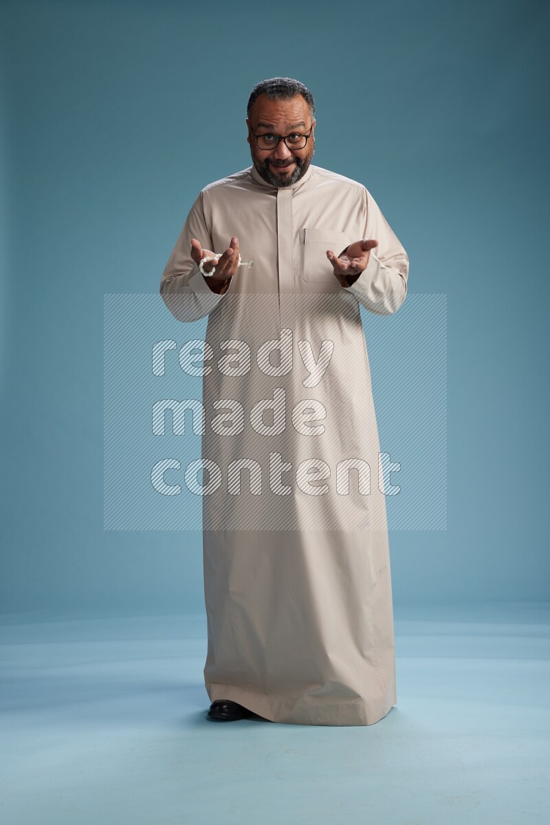 Saudi Man without shimag Standing Interacting with the camera on blue background