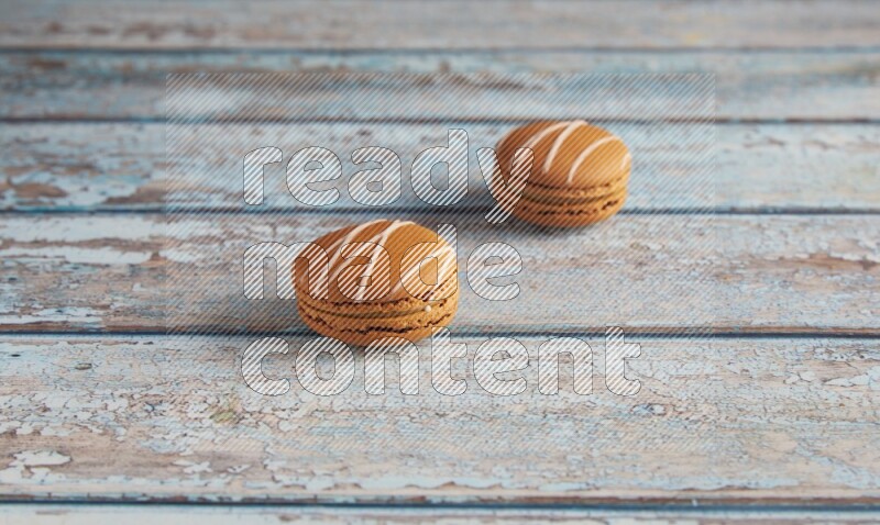 45º Shot of two Brown Irish Cream macarons on a  light blue wooden background
