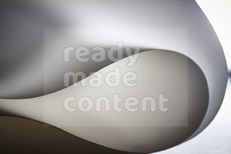An abstract art piece displaying smooth curves in grey gradients created by colored light