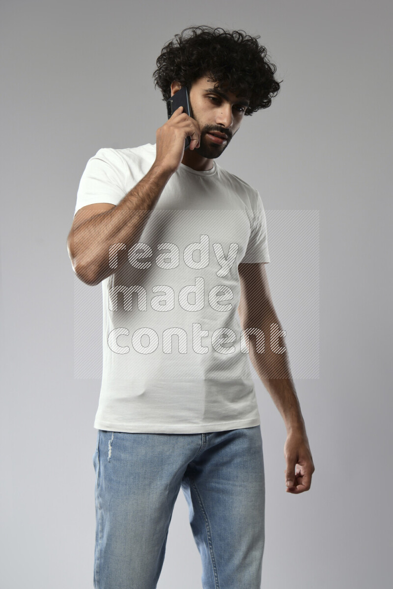 A man wearing casual standing and talking on the phone on white background