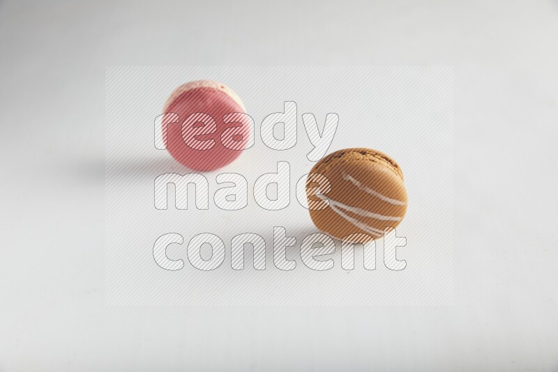 45º Shot of of two assorted Brown Irish Cream, and Pink Litchi Raspberry macarons on white background