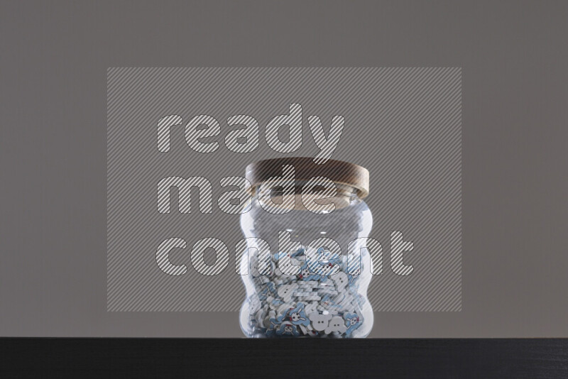 أزرار متنوعة في وعاء زجاجي علي خلفية سوداء