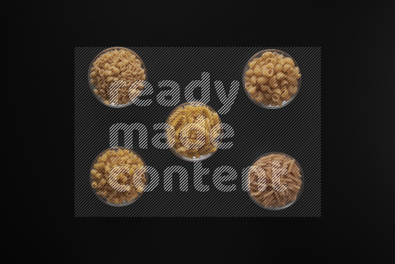 أنواع مختلفة من المعكرونة في أوعية زجاجية علي خلفية سوداء