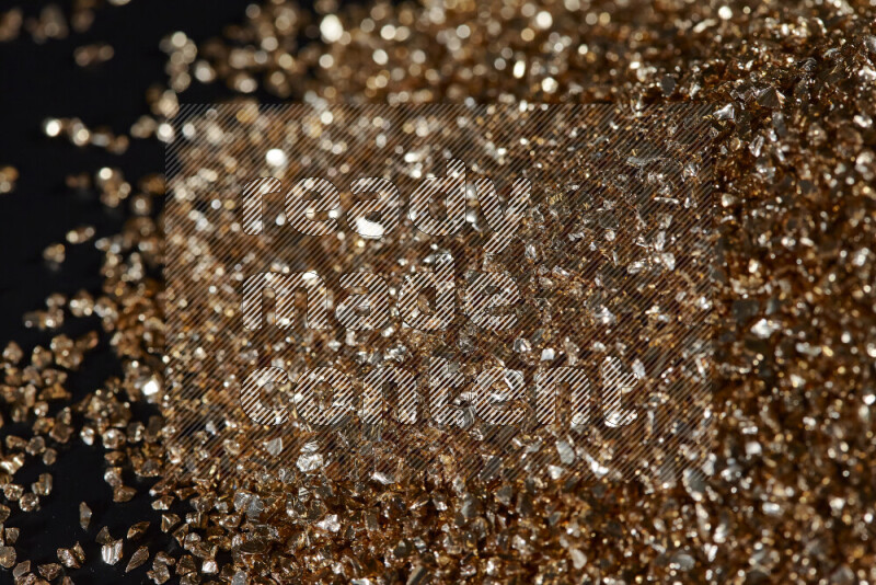 Gold shimmering fragments of glass scattered on a black background
