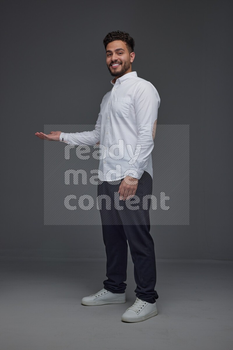 A man wearing smart casual standing and making multi hand gestures eye level on a gray background