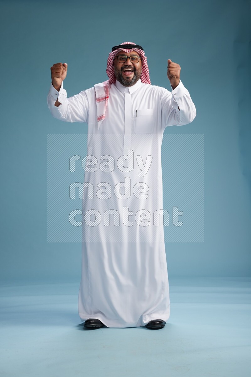 Saudi Man with shimag Standing Interacting with the camera on blue background
