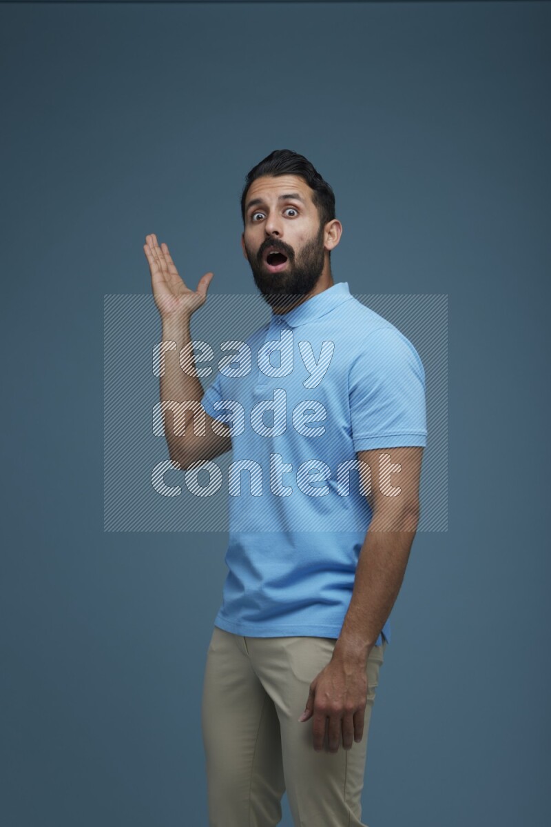 A man pointing  in a blue background wearing a Blue shirt