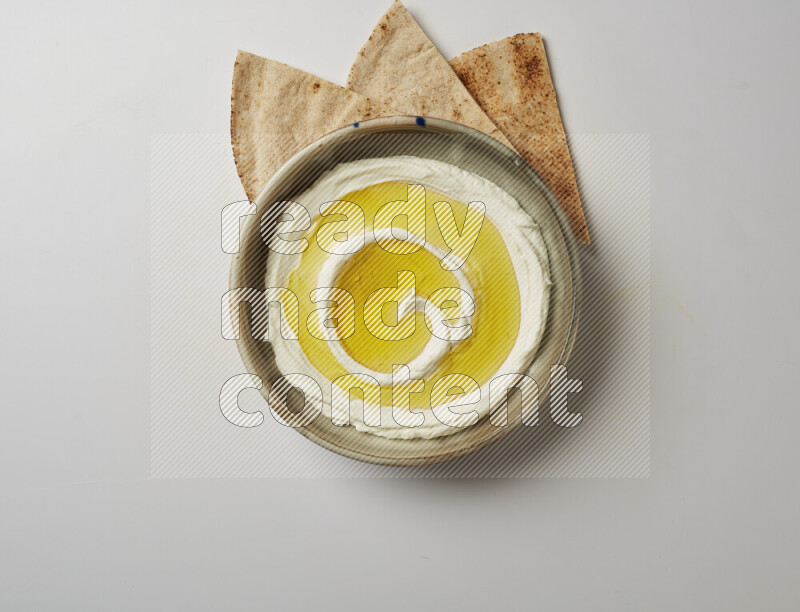 Lebnah garnished with olive oil in a grey pottery plate on a white background