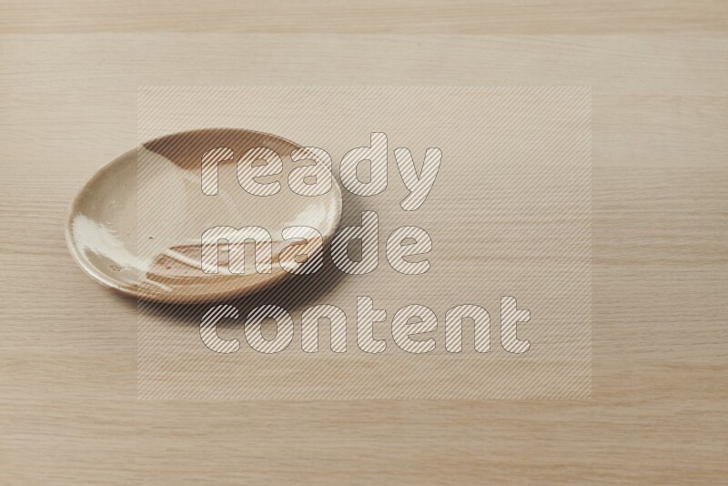 A beige pottery plate on light wooden background