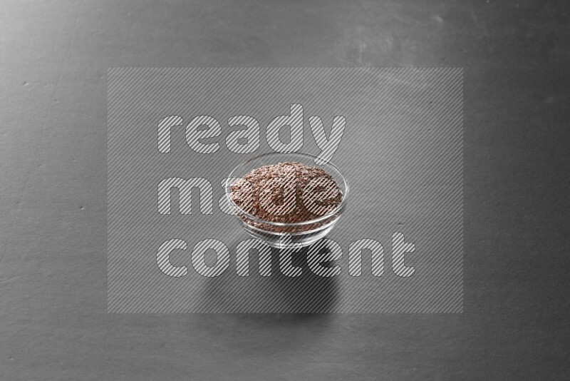 A glass bowl full of flax on black flooring