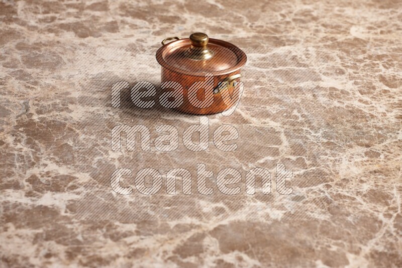 A small copper pot on beige marble background