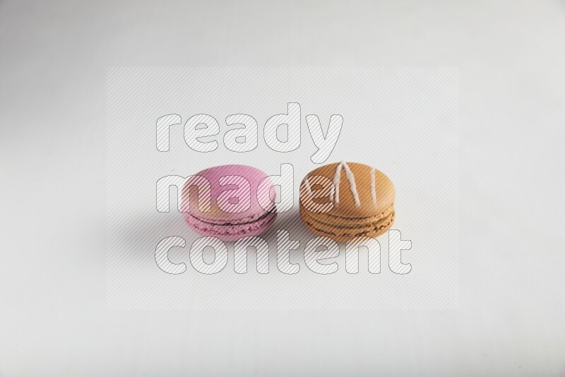 45º Shot of of two assorted Brown Irish Cream, and Purple Strawberry macarons on white background