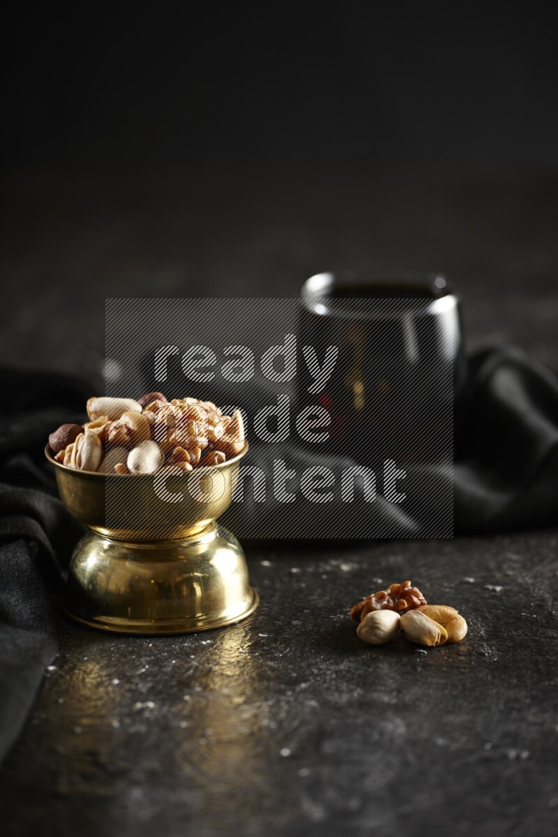 Nuts in a metal bowl with tamarind and a napkin in a dark setup