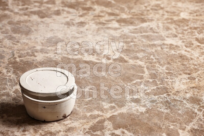 A white pottery bowl on beige marble background