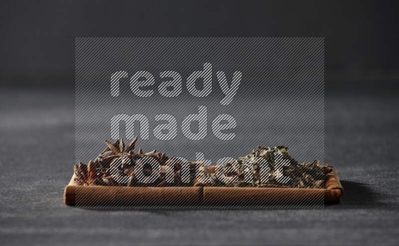 2 squares of cinnamon sticks full of star anise and dried basil on black flooring