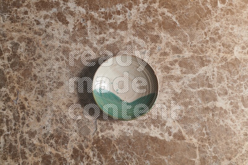 A decorative pottery plate on beige marble background