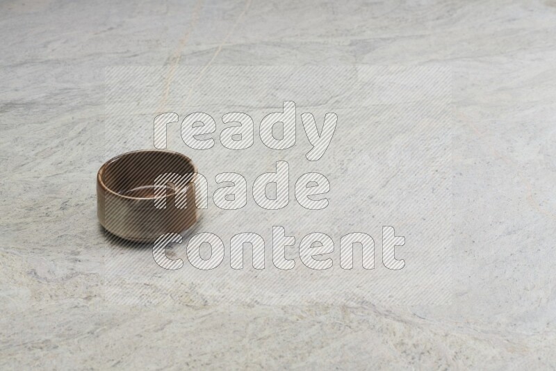 A brown pottery bowl on grey marble background