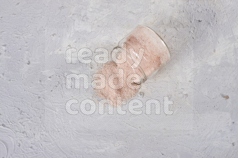A glass jar full of fine himalayan salt on white background
