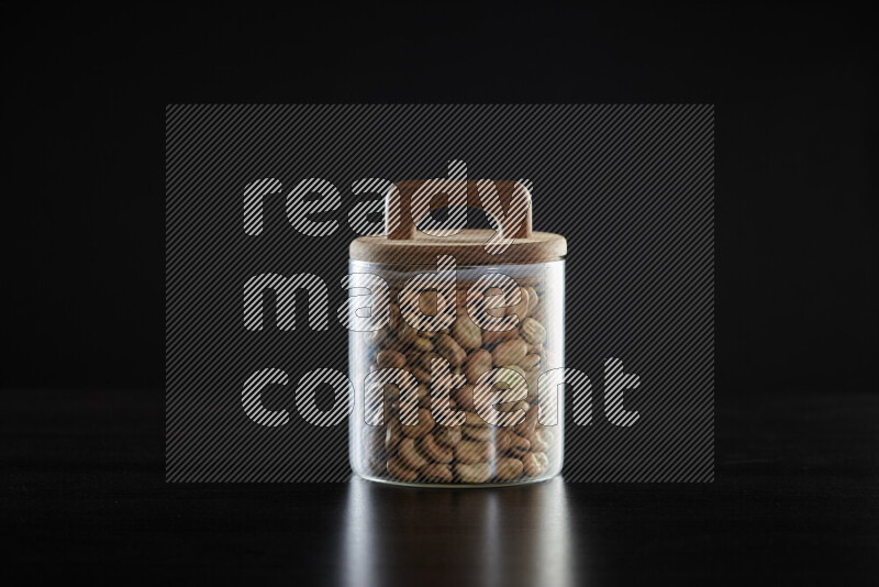 Fava beans in a glass jar on black background