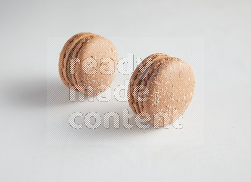 45º Shot of two Brown Hazelnuts macarons on white background