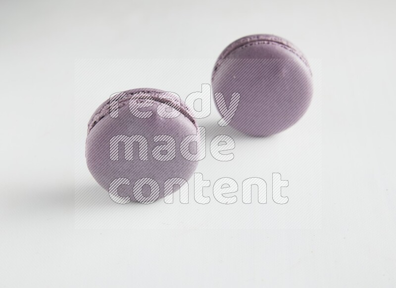 45º Shot of two Purple Blueberry macarons on white background