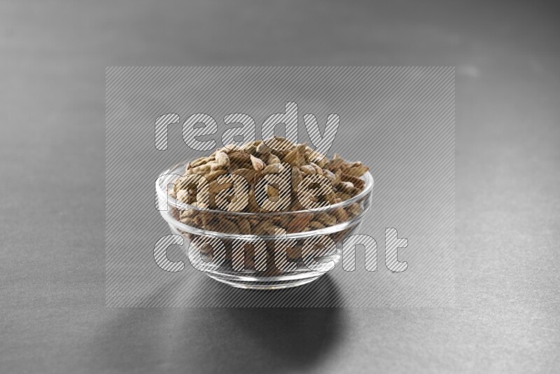 A glass bowl full of cardamom on black flooring