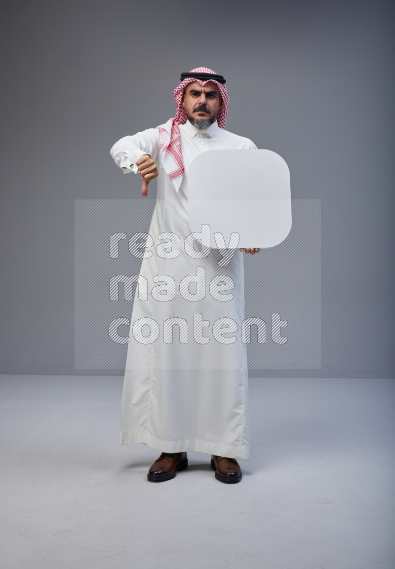 Saudi man Wearing Thob and red Shomag standing holding social media sign on Gray background