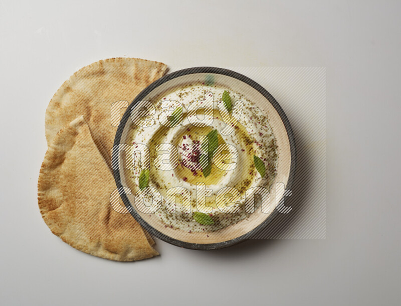 Lebnah garnished with zaater, mint & sumak in a pottery plate on a white background