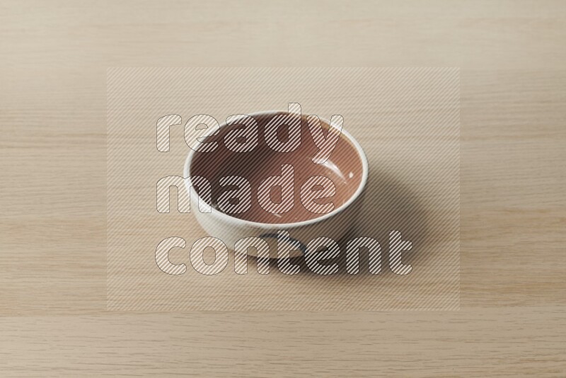 A brown pottery bowl on light wooden background