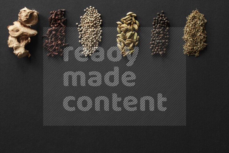 ginger, cloves, white pepper, cardamom, black pepper and Cumin lined on a Black background