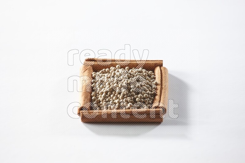 A single square of cinnamon sticks full of white pepper on white flooring