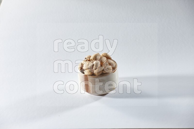 A beige ceramic bowl full of almonds on a white background in different angles