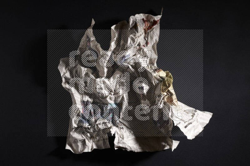 Crumpled newspaper sheet on black background