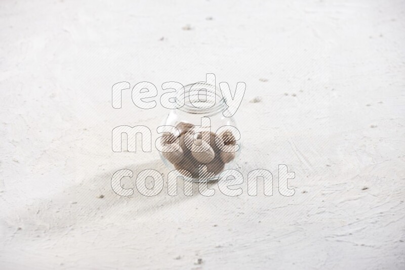 وعاء زجاجي ممتلئ بحبوب جوزة الطيب الكاملة علي خلفية بيضاء