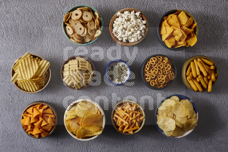 Assorted snacks in pottery bowls on grey background