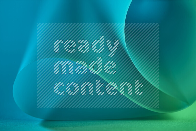 An abstract art piece displaying smooth curves in green and blue gradients created by colored light