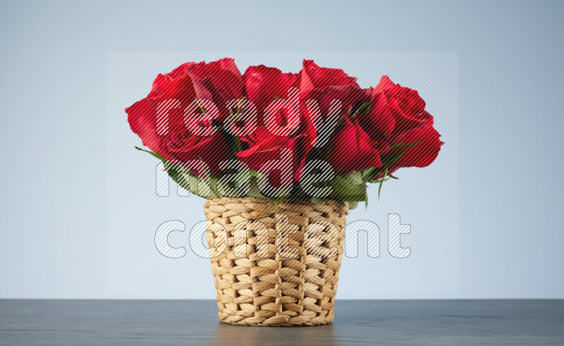 Vibrant red roses in a wicker basket on black marble background