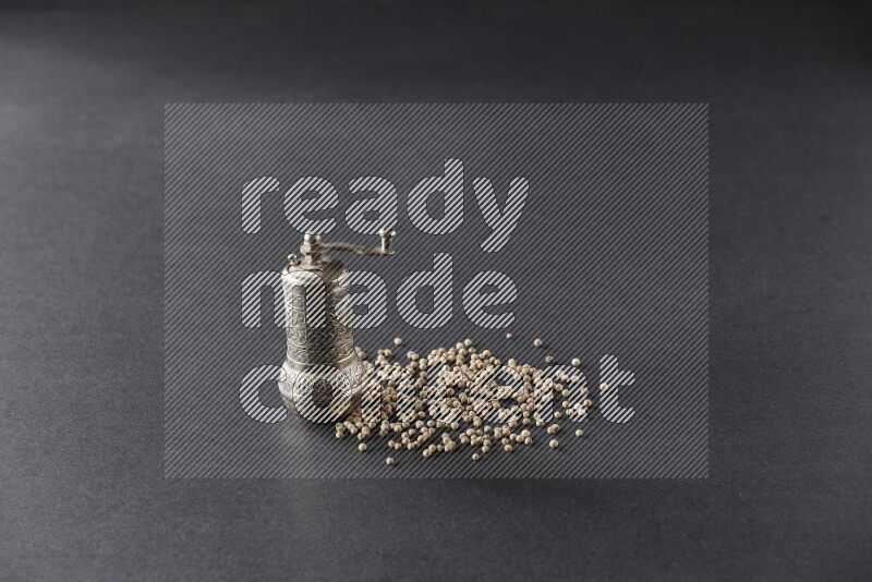 White pepper with a metal pepper grinder on black flooring