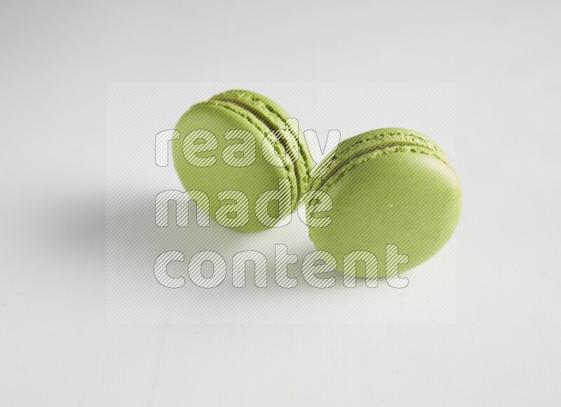 45º Shot of two Green Pistachio macarons on white background