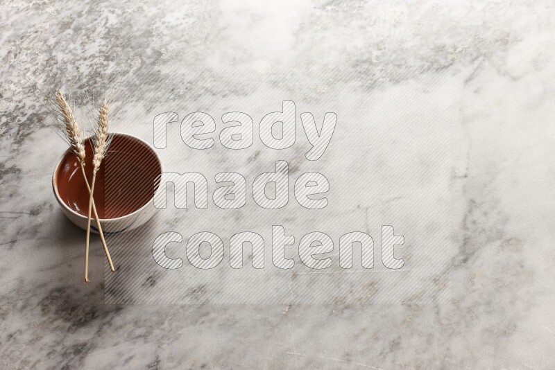 Wheat stalks on brown pottery bowl on grey marble background