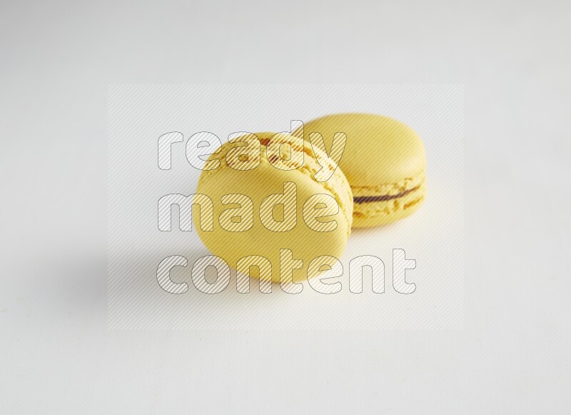 45º Shot of two Yellow Lemon macarons on white background