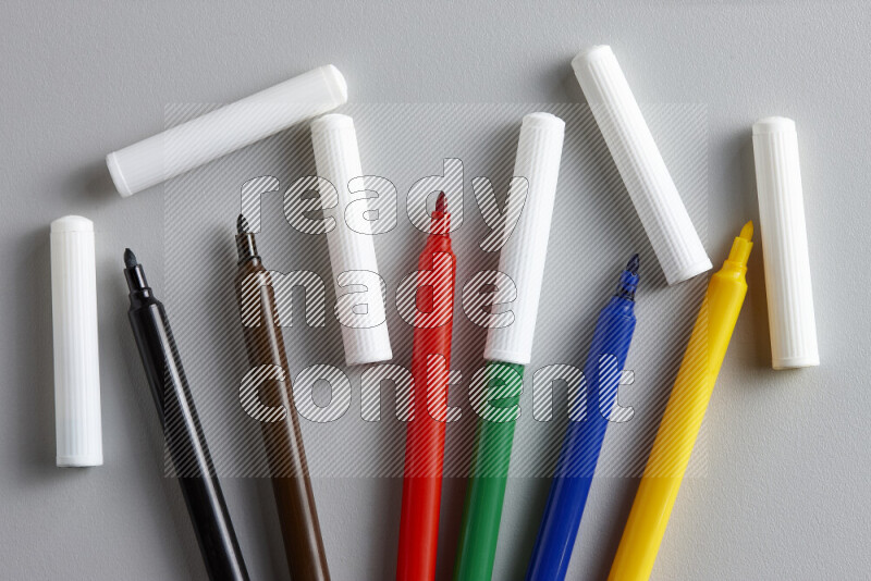 An arrangement of coloring pens in different colors on grey background