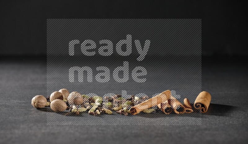 الهيل والقرنفل وجوزة الطيب وأعواد القرفة على خلفية سوداء